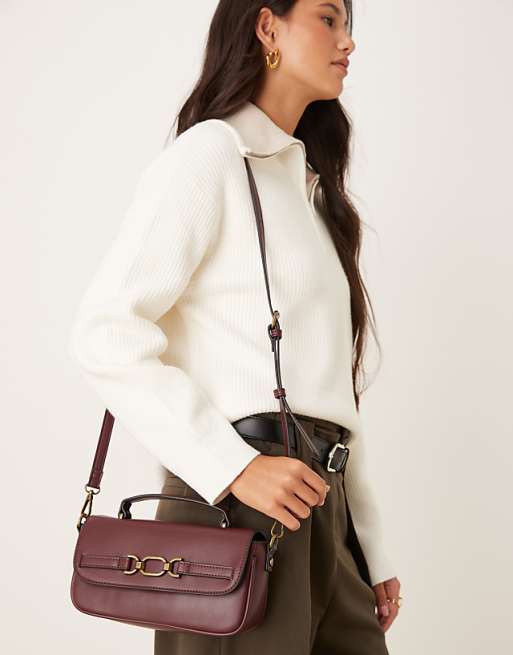 Accessorize crossbody bag with gold buckle detailing in burgundy